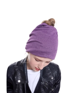 Dettaglio del berretto in maglia viola scuro indossato come fascia larga versatile