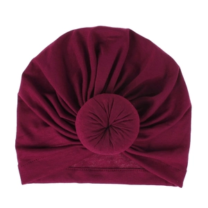 Macro detail of wine red knitted baby turban hat with a signature donut knot design