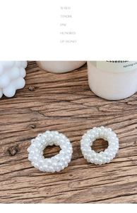 Detailed view of two white pearl hair scrunchies on a natural dark wood surface