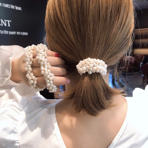 Elegant pearl hair tie and bracelet set shown on model in a stylish indoor setting