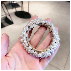 Close-up of elegant beige elastic hair tie with white faux pearl embellishments