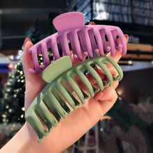 Close-up of large matte hair claws in purple and green held to show size and texture