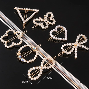 Detail view of gold alloy hair clips set with white pearls and sparkling rhinestones