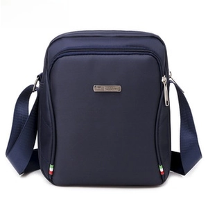 Front detail of navy blue canvas chest bag featuring metal logo and zipper pocket