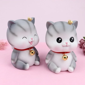 Detail showing two grey resin angel cat figurines with gold crowns and bells for home decor