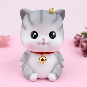 Cute gray and white angel cat piggy bank with golden crown and red bell collar on pink background