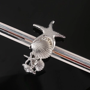 Detailed close-up of silver sea star and shell hair clip with textured metallic finish