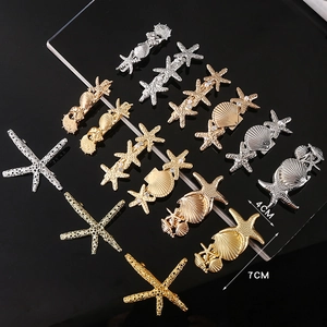 Gold and silver ocean style starfish hair clips with pearls and shell textures on black base