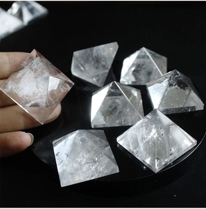 Close-up of a hand holding a clear natural white crystal pyramid for energy healing