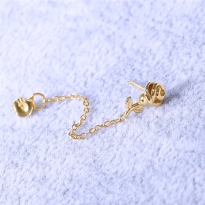 Macro shot of S925 engraved gold rose stud earring with fine tassel chain on purple fabric