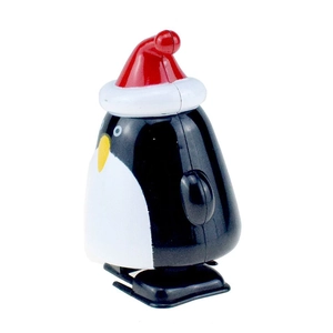 Close-up of a clockwork penguin toy with a red Christmas hat on a white background