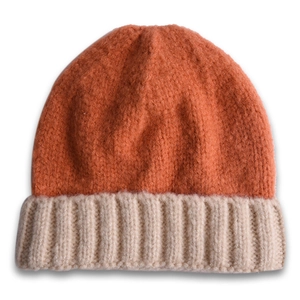 Gros plan du bonnet en maille côtelée bicolore montrant la texture épaisse orange et avoine