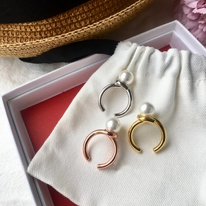 Three twisted freshwater pearl rings in silver, gold, and rose gold on a soft pouch