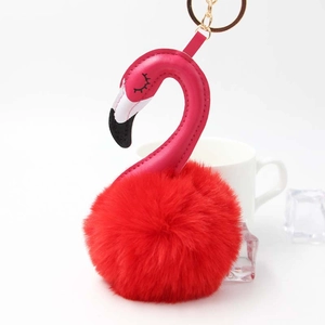 Close-up of flamingo pompom keychain with red fur body and gold hardware details