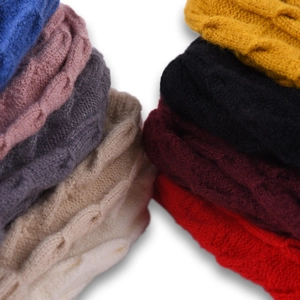 Pile of colorful cable-knit beanies showing rich textures and various solid color options