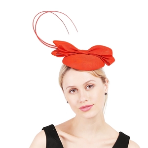 Detail view of a vintage red fascinator hat featuring a bow and delicate red feathers