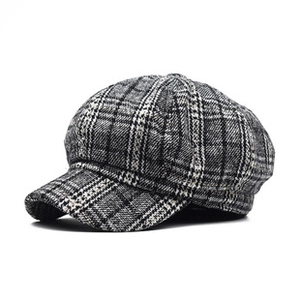 Close-up of the vintage grey plaid pattern and fine stitching on a classic baker boy hat