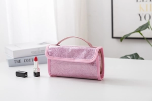 Detailed view of pink sequin cosmetic bag with a handle on a modern white desk