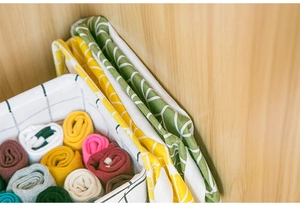 Top view of foldable cotton linen storage bins with leaf patterns in a wooden drawer