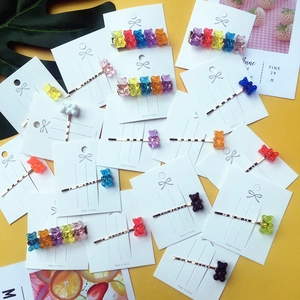 Flat lay of colorful acrylic gummy bear hair clips in rainbow colors on a yellow background