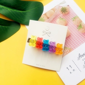 Detailed shot of five colorful gummy bear hair clips on a golden metal base with packaging