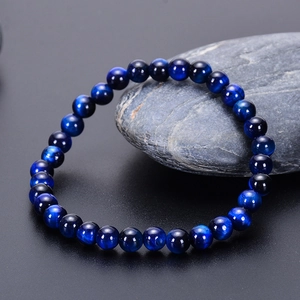 Close-up of natural blue tiger eye stone beads bracelet on dark stone display