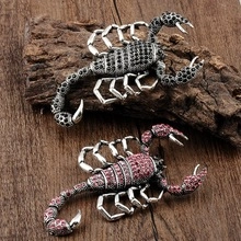Close-up of silver scorpion brooches with black and pink rhinestones on dark wood
