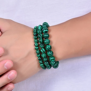 Three stacked natural malachite beaded bracelets worn by a model on white background