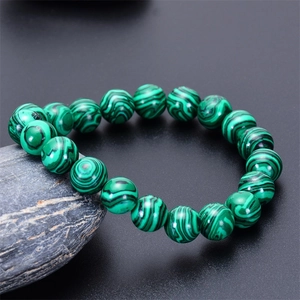 Macro shot of green malachite beaded bracelet with unique textures on dark stone
