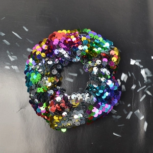 Detailed view of rainbow-colored flip sequin hair scrunchie with sparkling disco style