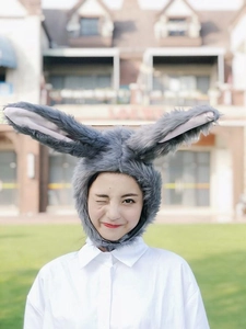Close-up of cute grey plush rabbit ear headband worn by a model in outdoor setting