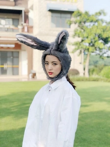 Close-up of soft grey plush bunny ears hat worn by a model in outdoor natural lighting