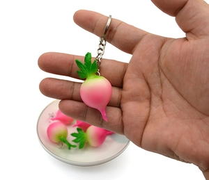Close-up of pink radish PVC keychain with realistic green leaves and metal ring