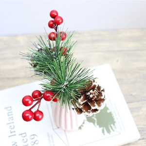 Artificial Christmas decoration featuring red berries, pine needles, and pine cones in a vase