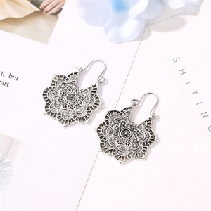 Détail de boucles d'oreilles mandala argentées avec des motifs de fleurs ajourés rétro