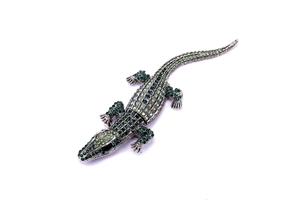 Close-up of crocodile brooch featuring gradient green rhinestones and silver metal base