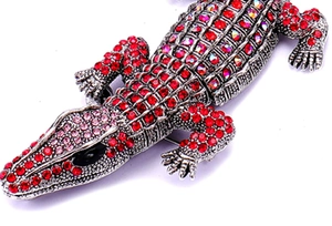 Macro shot of silver plated crocodile brooch with red and pink rhinestone crystals