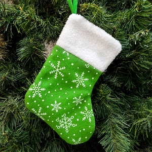 Green snowflake Christmas stocking gift bag with plush white trim hanging on a tree