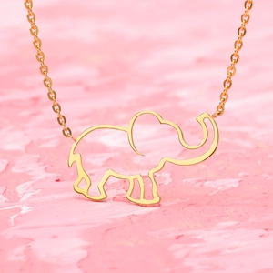 Minimalist gold hollow elephant pendant necklace on a textured pink background