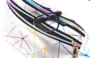 Macro shot of iridescent silver geometric waist bag showing dual zippers and interior storage