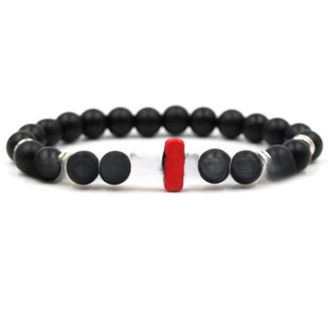 Detail of beaded bracelet featuring matte black beads and a red cross charm centerpiece