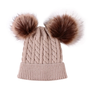 Detail of knitted baby hat texture with dual large dark brown faux fur pom poms