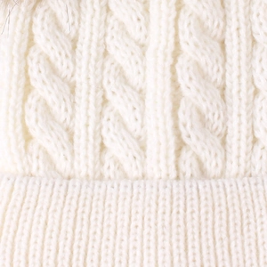 Detailed close-up of white knitted baby hat showing cable and ribbed textures