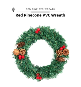 Détail d'une couronne de Noël en PVC vert avec des baies rouges et des pommes de pin