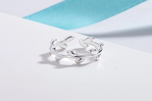 Detailed view of adjustable silver olive branch ring on white surface with blue ribbon