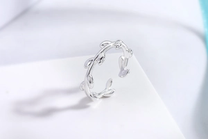 Detailed close-up of a silver olive branch ring with polished leaf texture on a white base