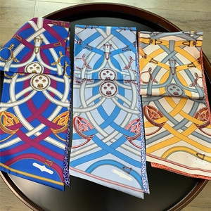 Three equestrian print silk scarves in royal blue, light blue, and ginger on black tray
