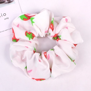 Flat lay of a white fabric scrunchie with red strawberry patterns and a decorative card