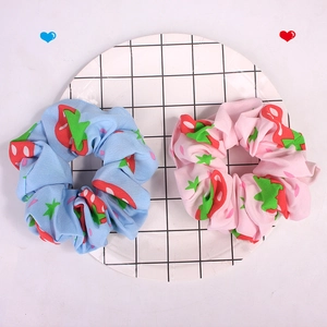 Detail of pink and blue strawberry print fabric scrunchies on a white grid tray