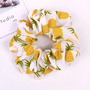 Close-up of fabric scrunchie with yellow pineapple pattern and pleated texture details